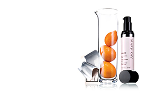 An open TimeWise Vitamin C Activating Square packet leaning on a glass tube holding three oranges next to TimeWise Tone-Correcting Serum balancing on its cap. 