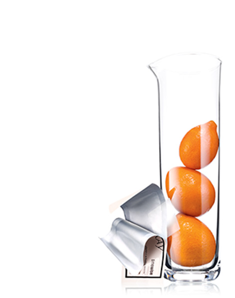 An open TimeWise Vitamin C Activating Square packet leaning on a glass tube holding three oranges.