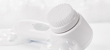 Skinvigorate Sonic™ Skin Care System from Mary Kay lying next to bubbles.