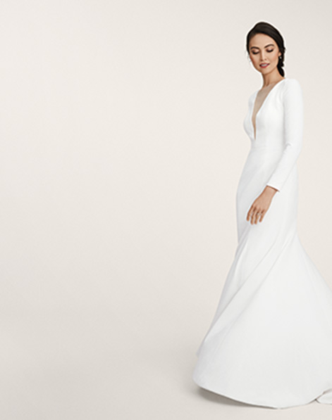 Model in wedding gown wearing Polished Beauty bridal makeup look from Mary Kay standing against beige background