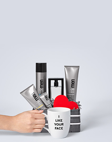 MKMen Skin Care Regimen, Cityscape Cologne Spray and a red heart styled in a gray gift box, behind a hand holding a mug that says I like Your Face.