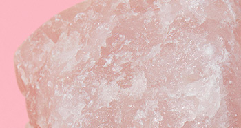 Close up of rose quartz to represent dry skin on a pink background