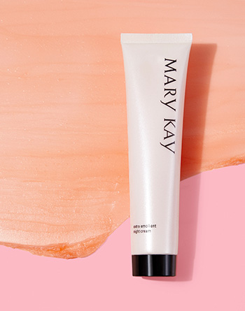 Up close tube of Mary Kay® Extra Emollient Night Cream moisturizer for dry skin on pink product rub background