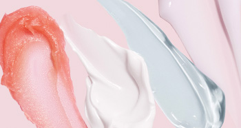 Multiple product rubs of face cream and moisturizer for dry skin on a pink background