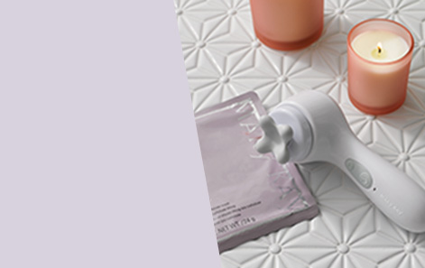 Mary Kay Skinvigorate Sonic Skin Care System and facial massage head shown on white floral bathroom tile with white candles in pink glass and Mary Kay TimeWise Repair Lifting Bio-Cellulose Mask  