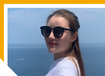 Image of Anne taking selfie wearing sunglasses with the ocean in the background