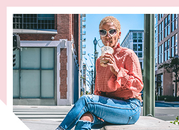 Image of woman sitting outside sipping a beverage through a straw