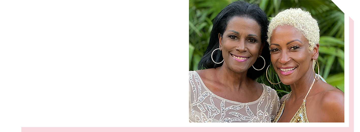 Image of two sisters smiling with palm leaves behind them
