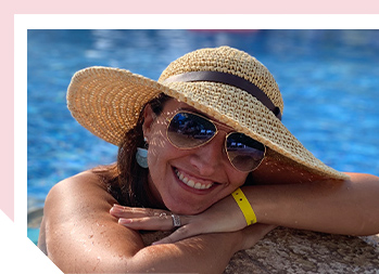 Image of woman in a hat and sunglasses smiling in a swimming pool