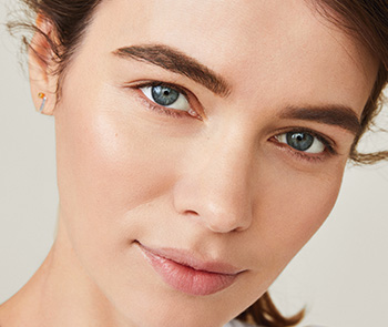 A picture of a white, brunette young woman touching her face