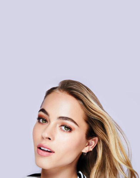 Model with bold brows and windswept hair posed off-center. 