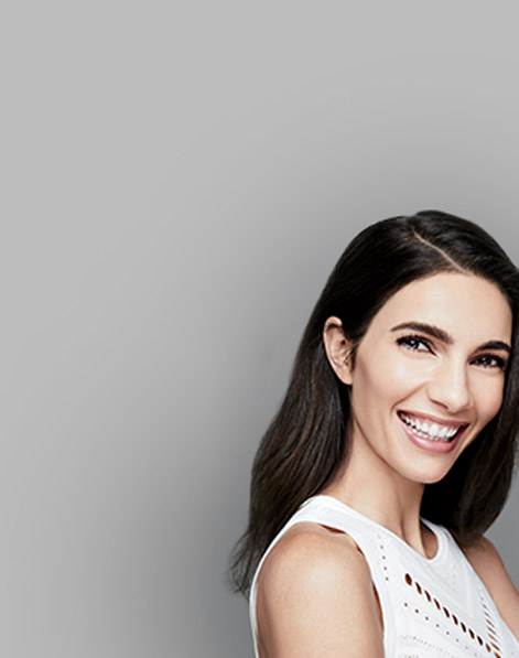 Woman with clear skin smiling against gray background displaying effects of Mary Kay skin care. 