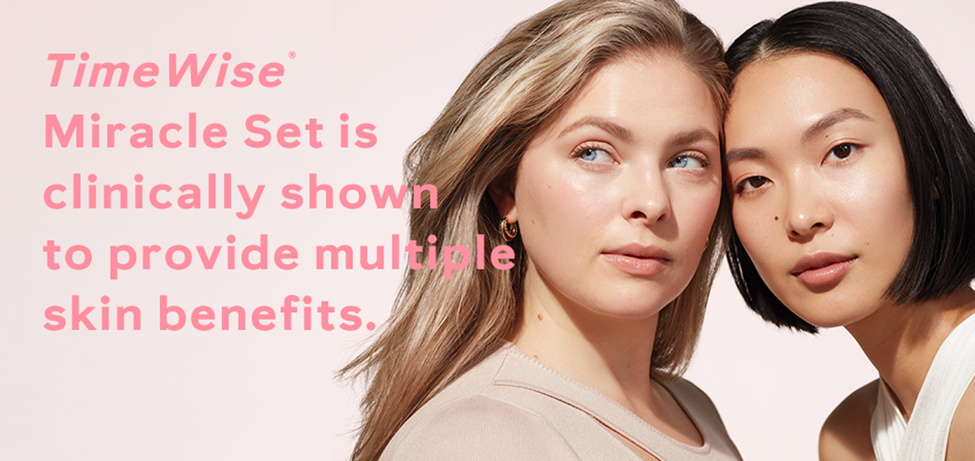 A blonde white woman and brunette Asian woman confidently posing closely together surrounded by sunlit lighting and a light pink background