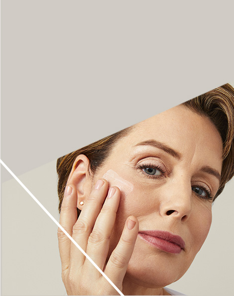 Mature model smoothing Mary Kay skin care product onto her cheek.