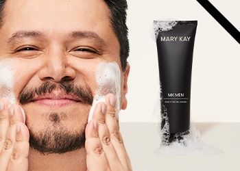 A dark-haired man with facial hair happily washing his face pictured next to MKMen Daily Facial Wash