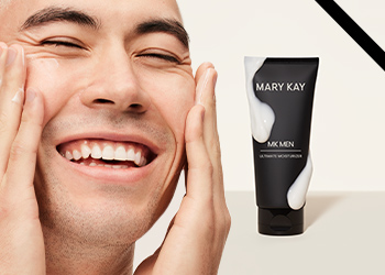 A young, dark-haired man happily moisturizing his skin pictured next to MKMen Ultimate Moisturizer