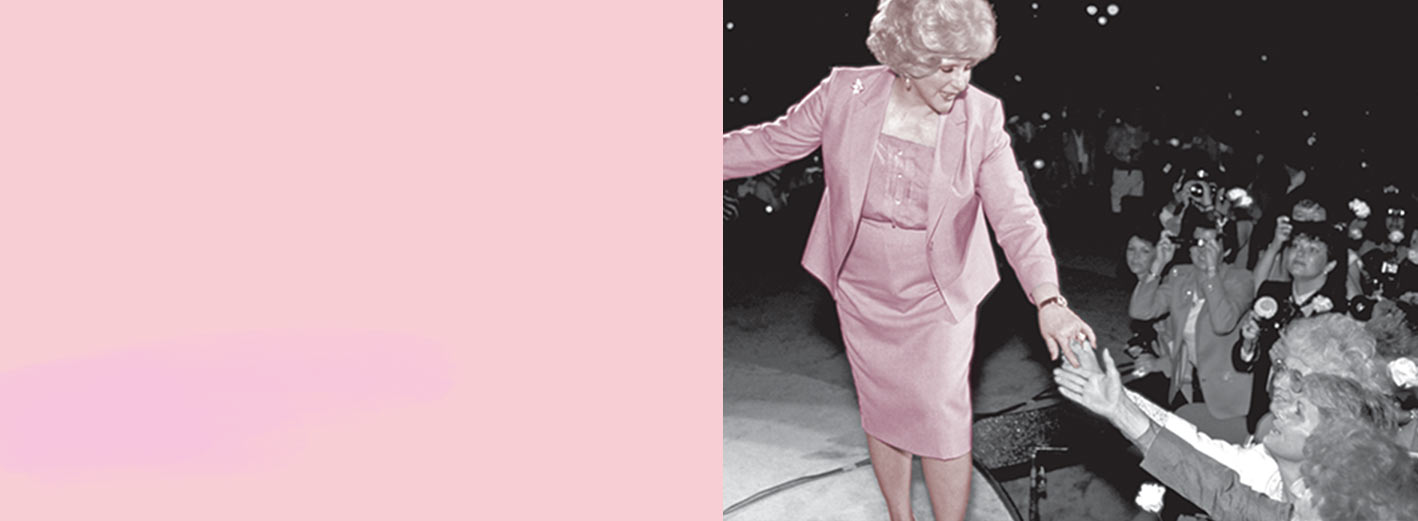 Mary Kay Ash stands on stage and reaches out to members of the Mary Kay independent sales force in an audience.