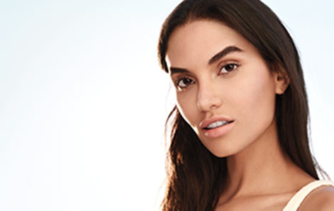 A woman with clear, beautiful skin and dark brown hair poses to promote Mary Kay skin care.
