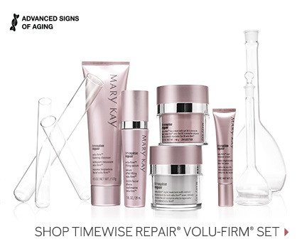 The TimeWise Repair Volu-Firm skin care set from Mary Kay is shown in front of clear glass beakers, including the Eye Renewal Cream, the Lifting Serum, the Foaming Cleanser, the Day Cream with SPF 30 and the Night Treatment with Retinol.