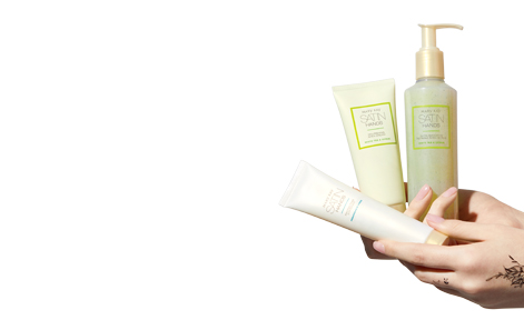 Satin Hand Set in White Tea & Citrus being held by a tattoo light-skinned hand on a plain white background